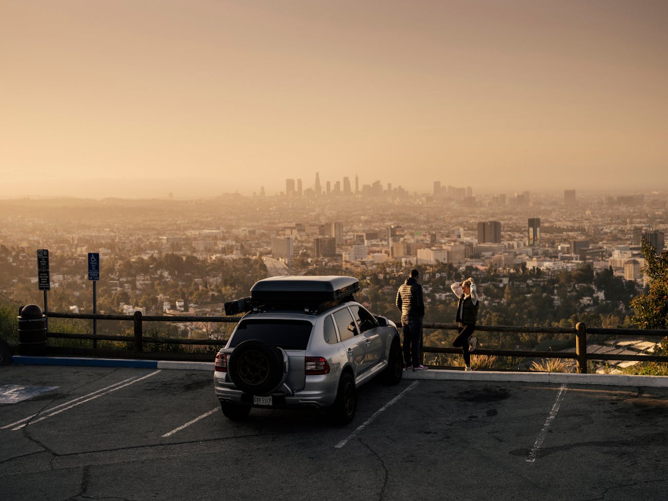 Couple with a Porsche Cayenne with LA skyline in background