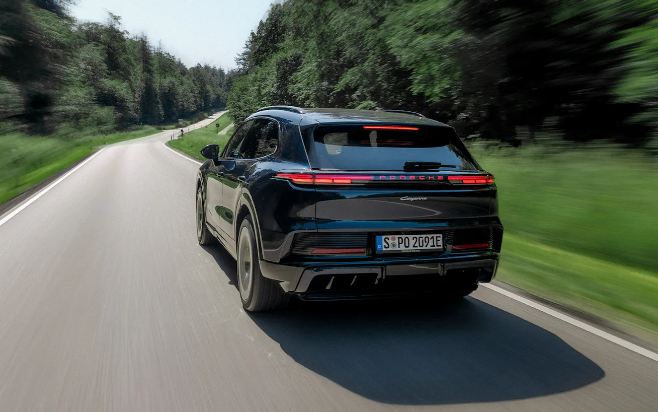 Rear view Porsche Cayenne Electric on tree lined rural road