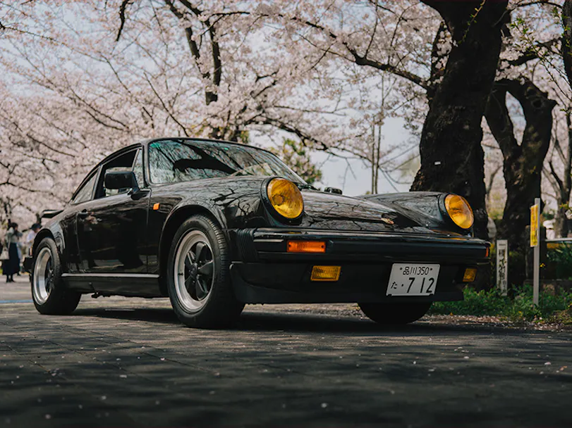Black classic Porsche 911 Carrera S/C driving on Tokyo street 