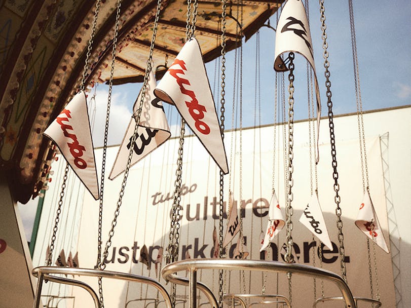 Merry-go-round decorated with white flags bearing the Porsche Turbo logo 