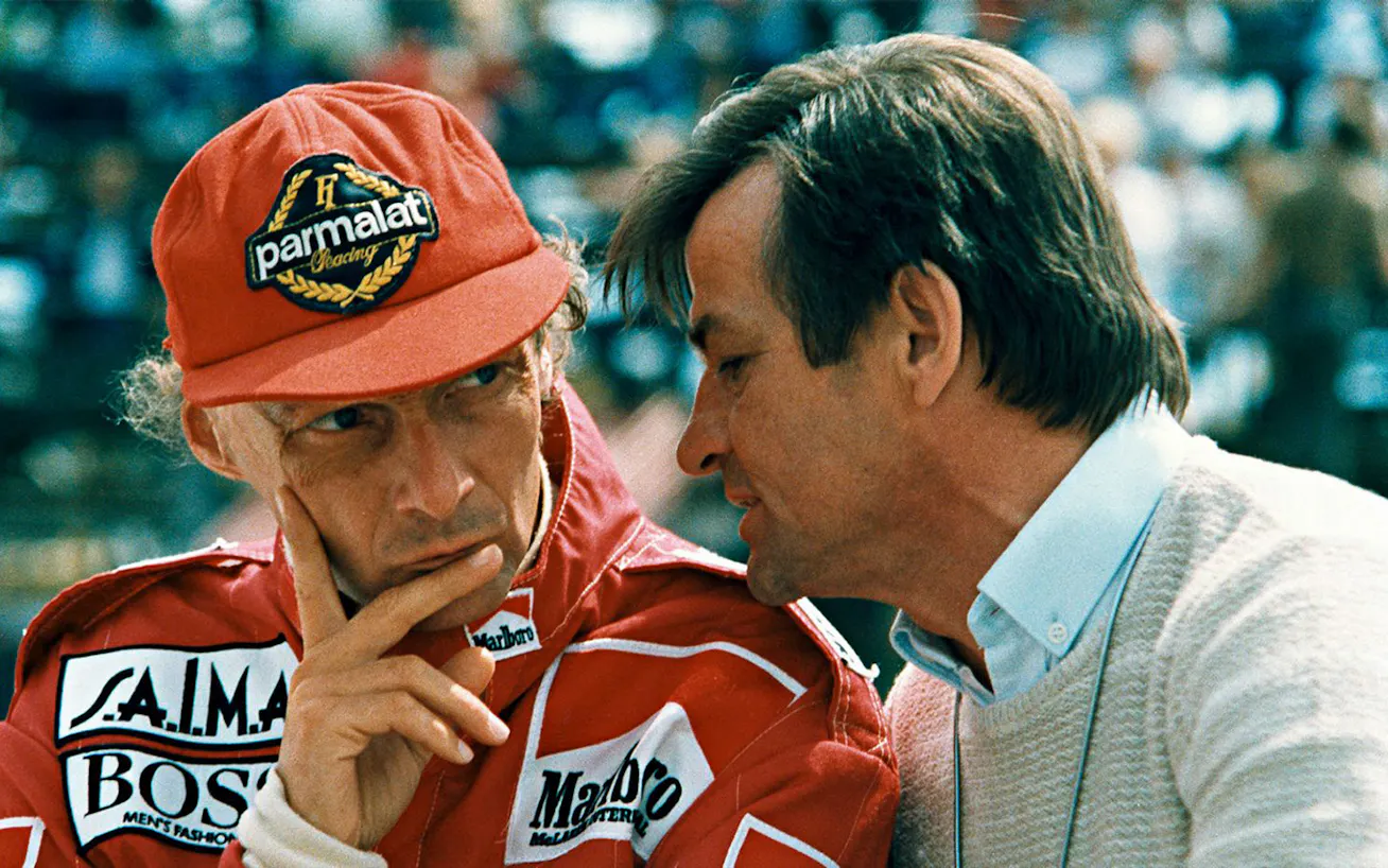 Hans Mezger talking to legendary McLaren driver Niki Lauda at a Formula One race 