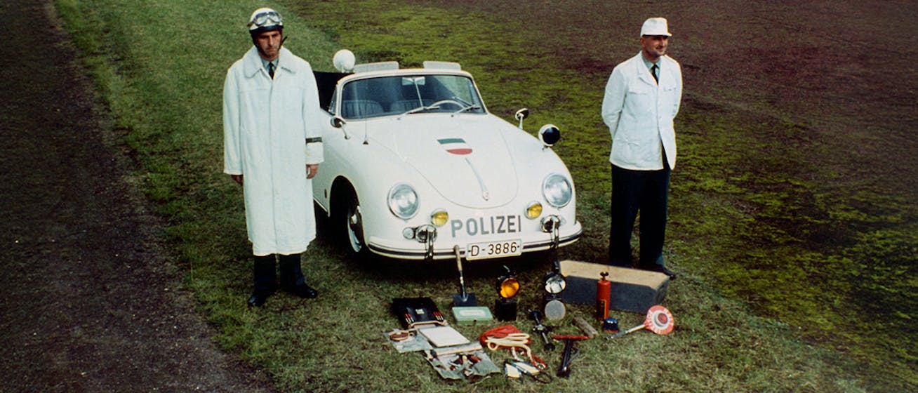 Two policemen standing with Porsche 356 Cabriolet police car