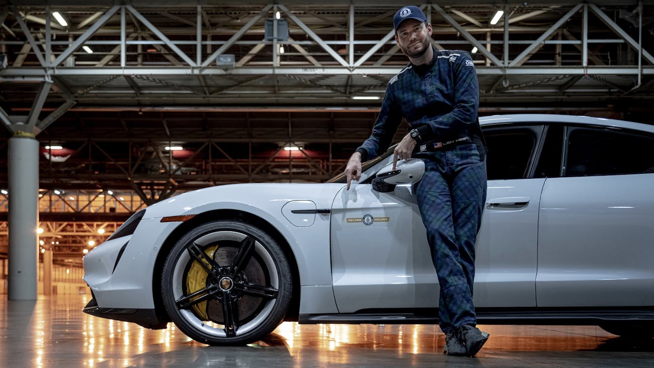 Driver stands besides record-breaking white Porsche Taycan Turbo S