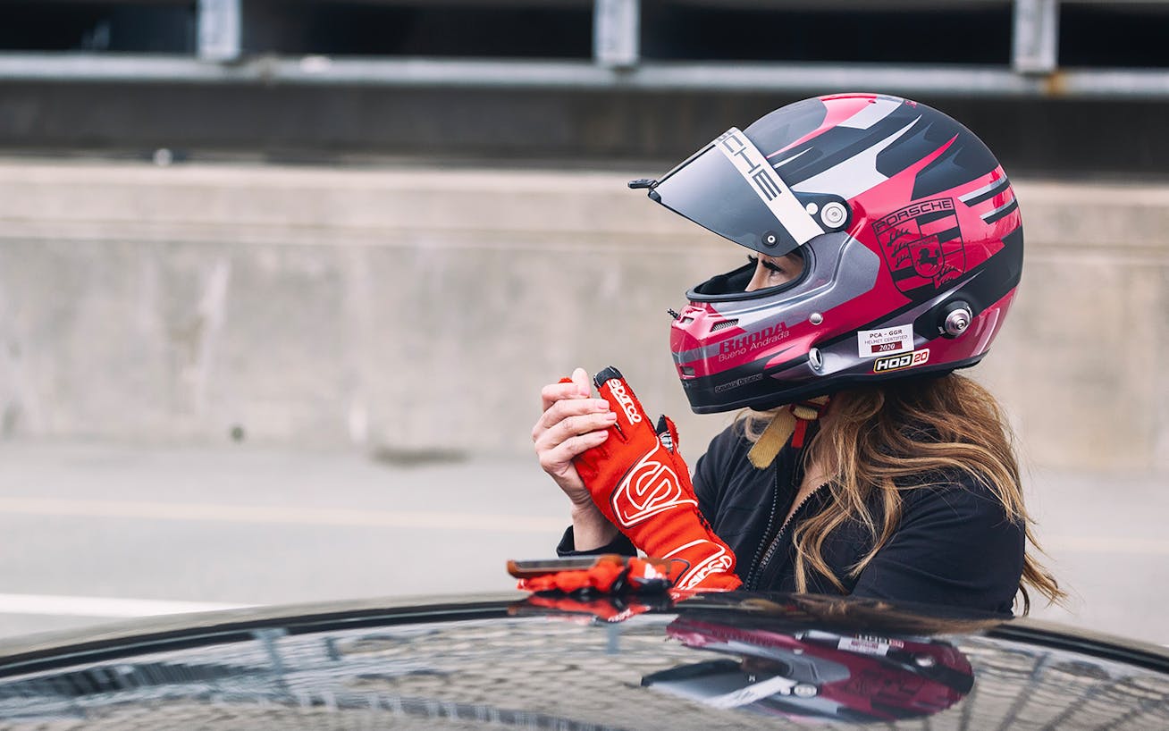 Close-up of woman in helmet next to car on track