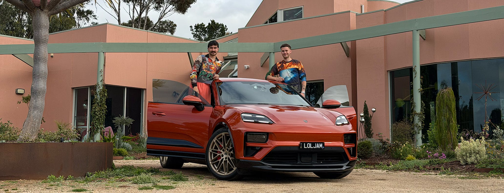 Two men with Porsche Macan Turbo Electric in Papaya Metallic 