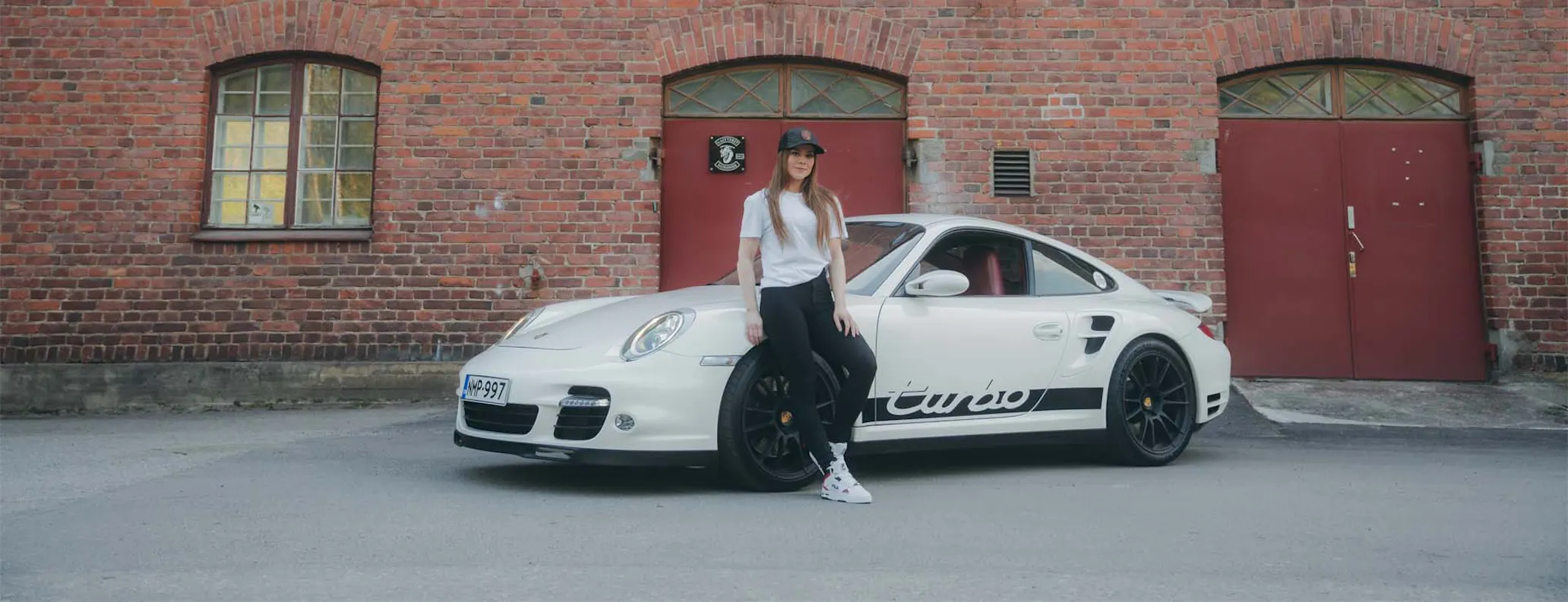Woman standing beside porsche 911 turbo hero desktop