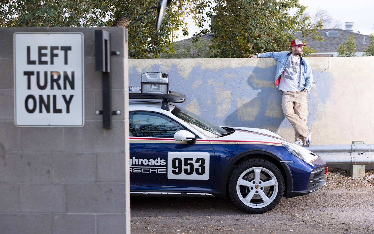 Artist Sean Wotherspoon, in baseball cap, next to Porsche 911 Dakar