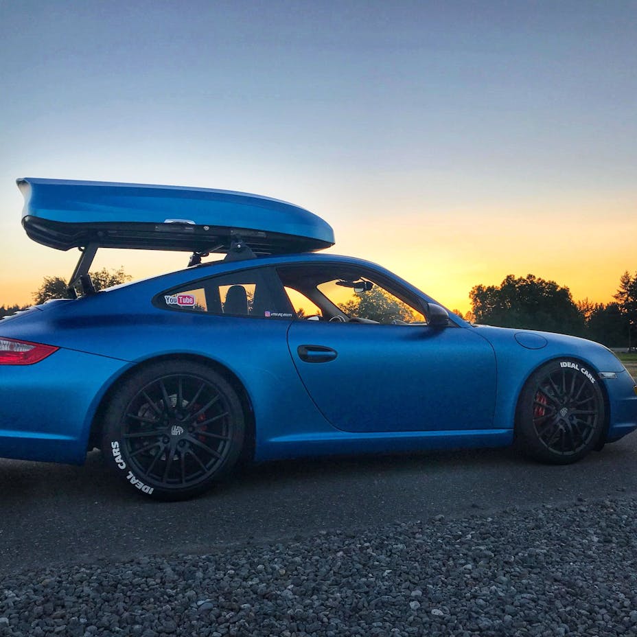 Blue 911 with rooftop ski box at sunset