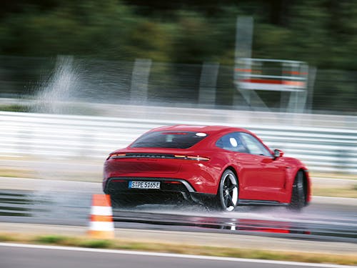 Red Porsche Taycan Turbo S corners on a racetrack