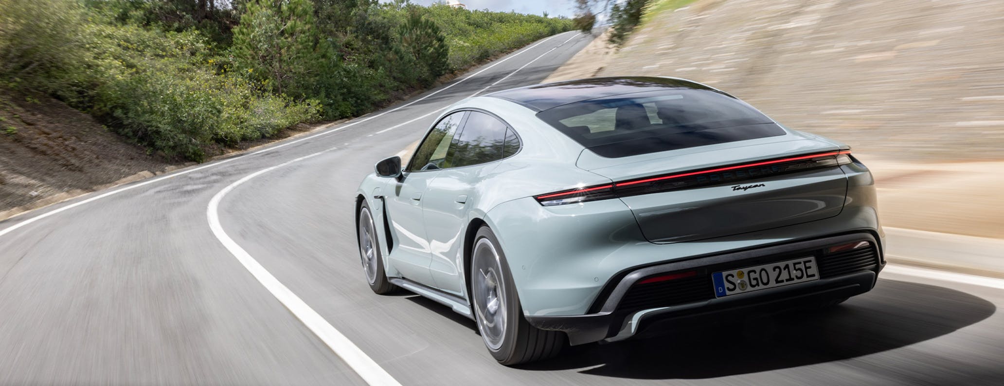 Porsche Taycan in Shade Green Metallic driving on Spanish road