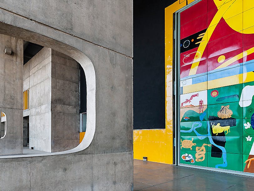Exposed concrete building with bright, expressive modern wall art 