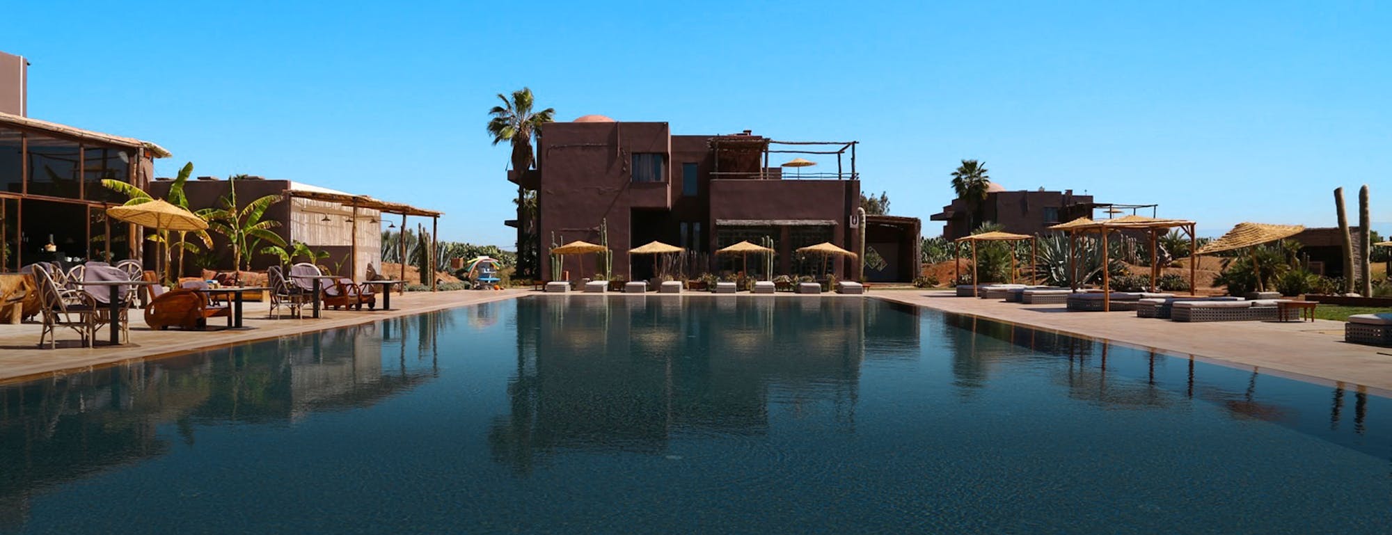 Hotel with pool in foreground, palms behind