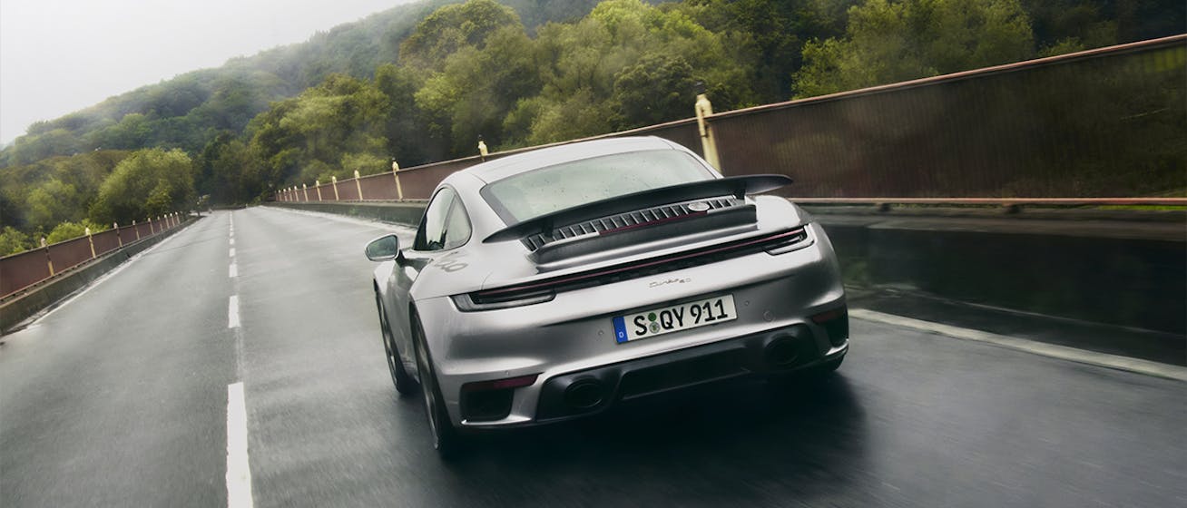 Rear view of silver Porsche 911 Turbo on the road 