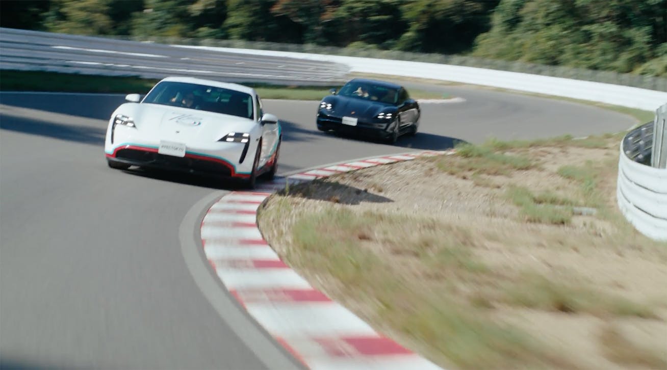 Two Porsche Taycan sportscars driving on the racetrack at the Porsche Experience Center Tokyo