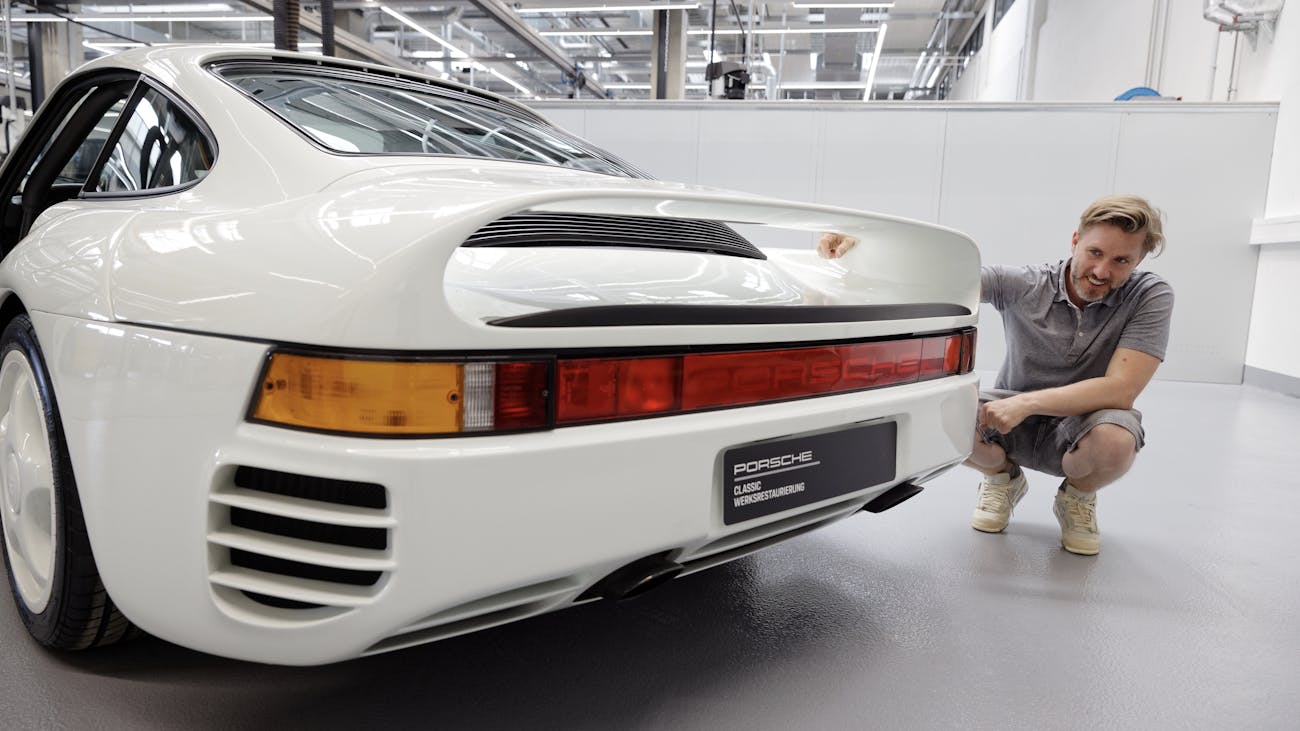 Nick Heidfeld squats beside rear of his white Porsche 959