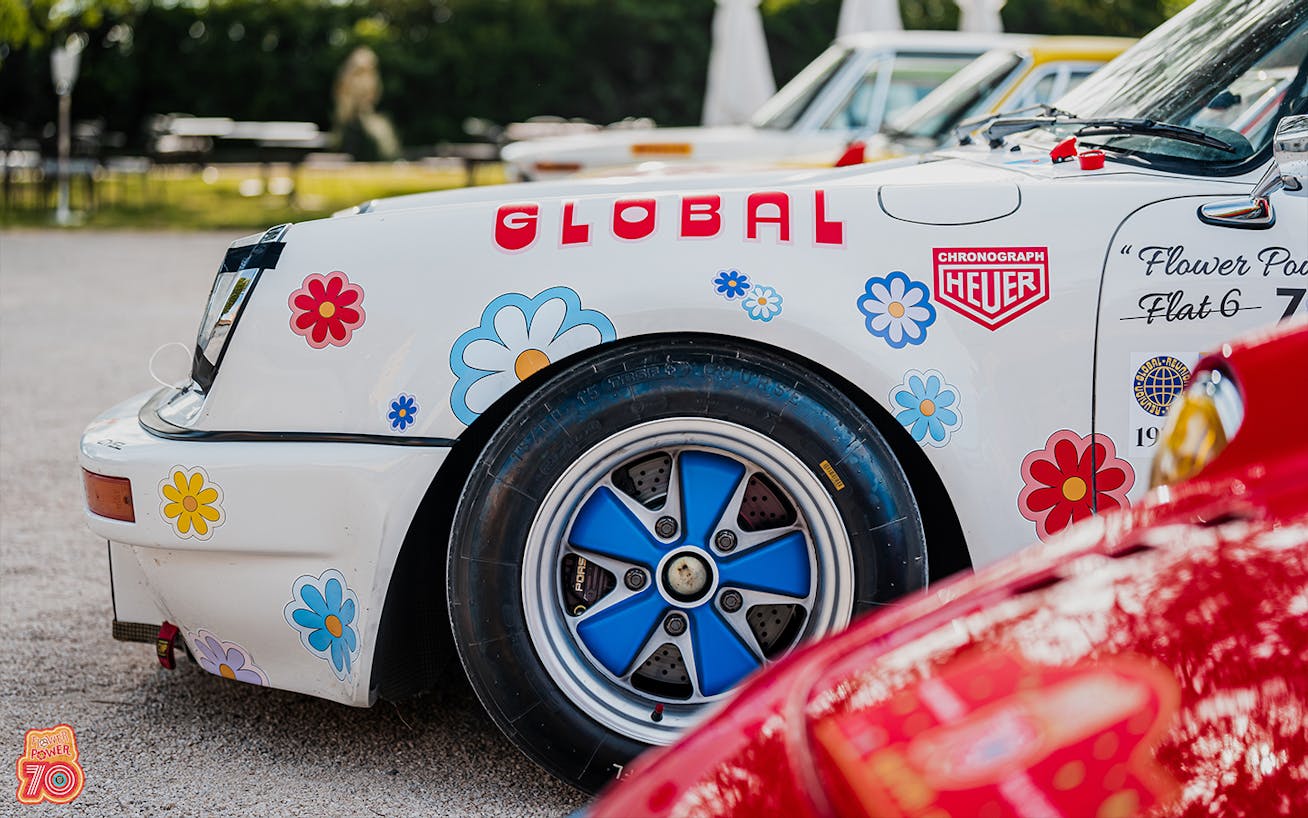 Close-up of Porsche art car with blue wheels and floral design 