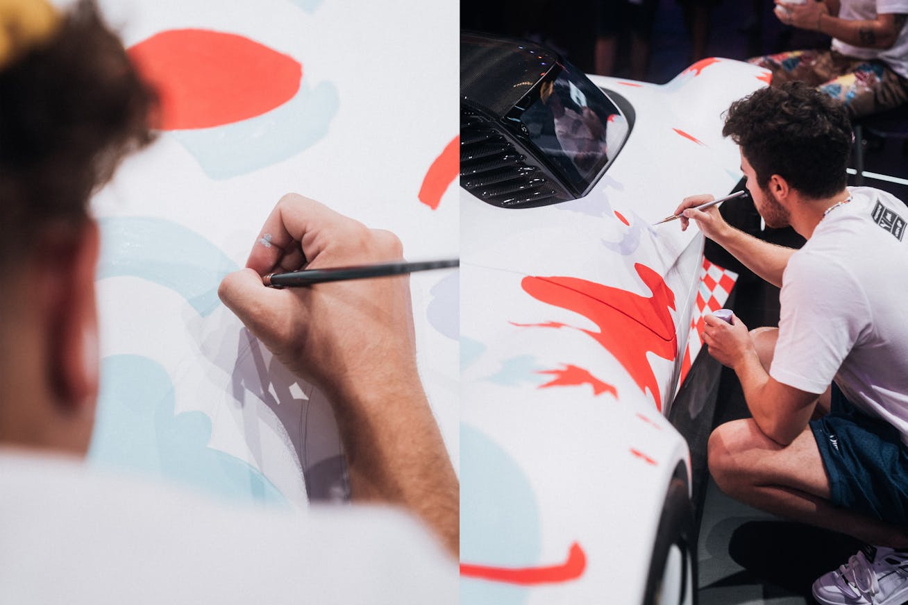 Artist painting light blue and red shapes onto Porsche concept car
