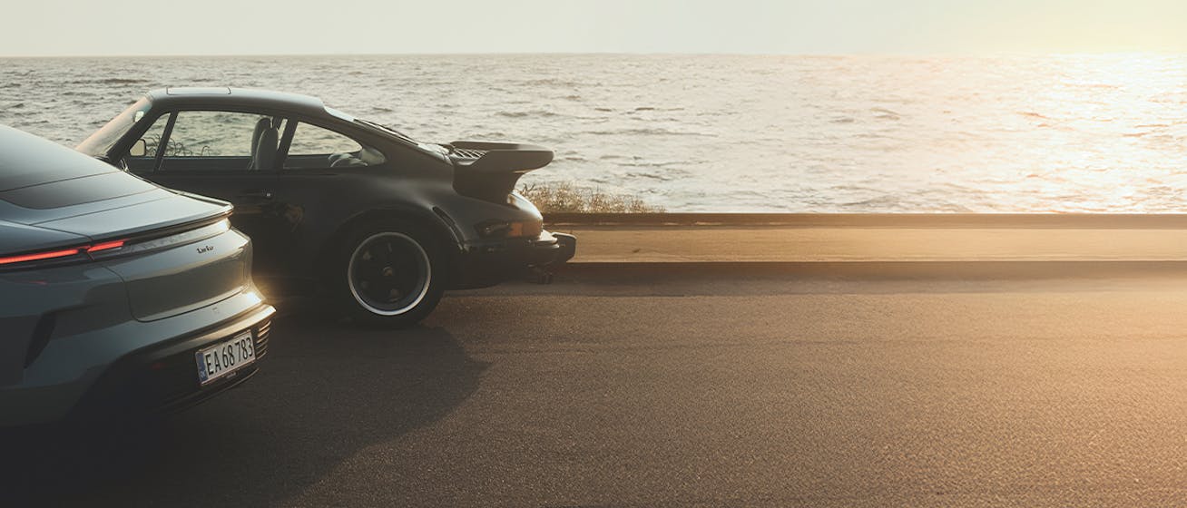Two Porsche 911 cars parked by the beach