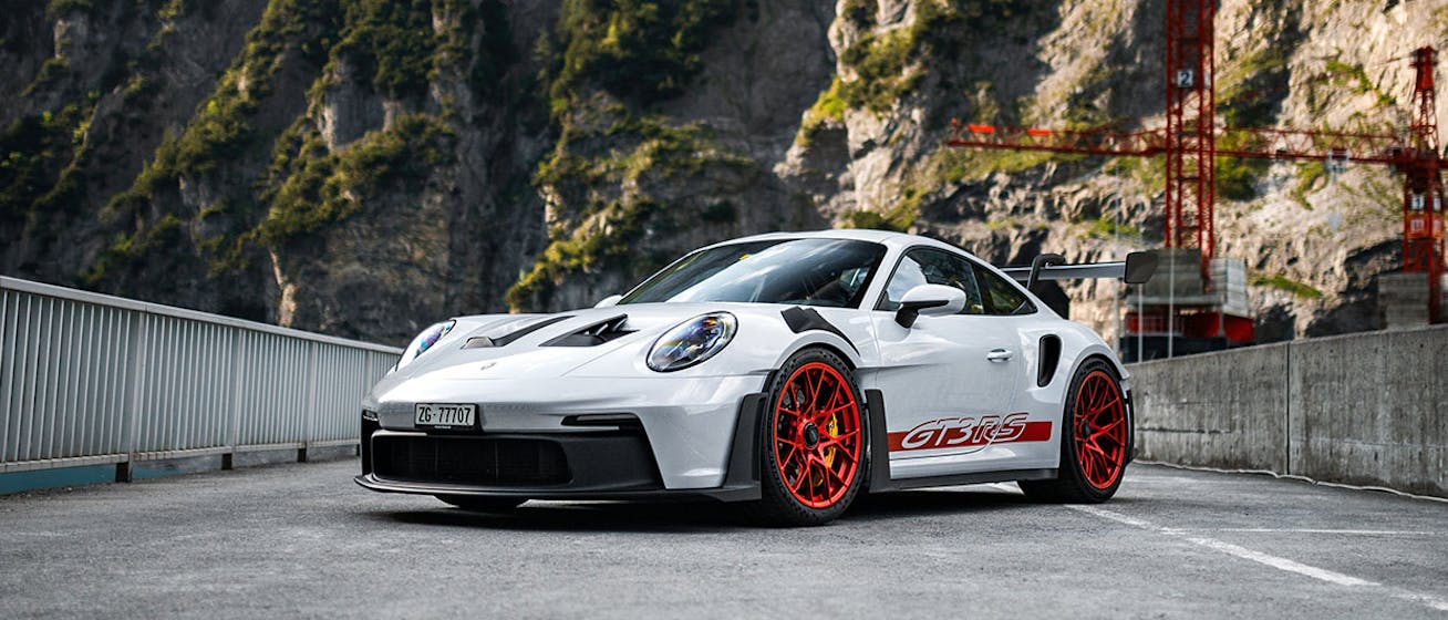 Porsche 911 GT3 RS parked on bridge, cranes behind