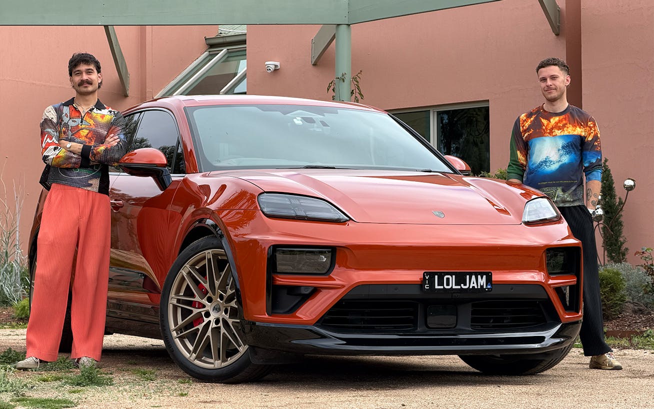Two men standing by Porsche Macan Turbo Electric outside house