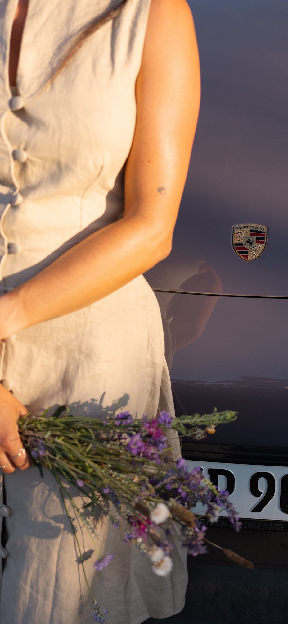 Close-up of person holding lavender, Porsche Macan behind