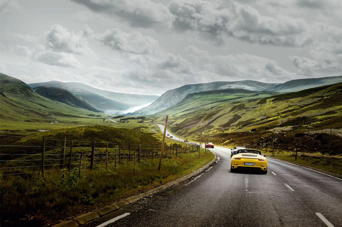 Porsche cars on winding valley roads through the Highlands