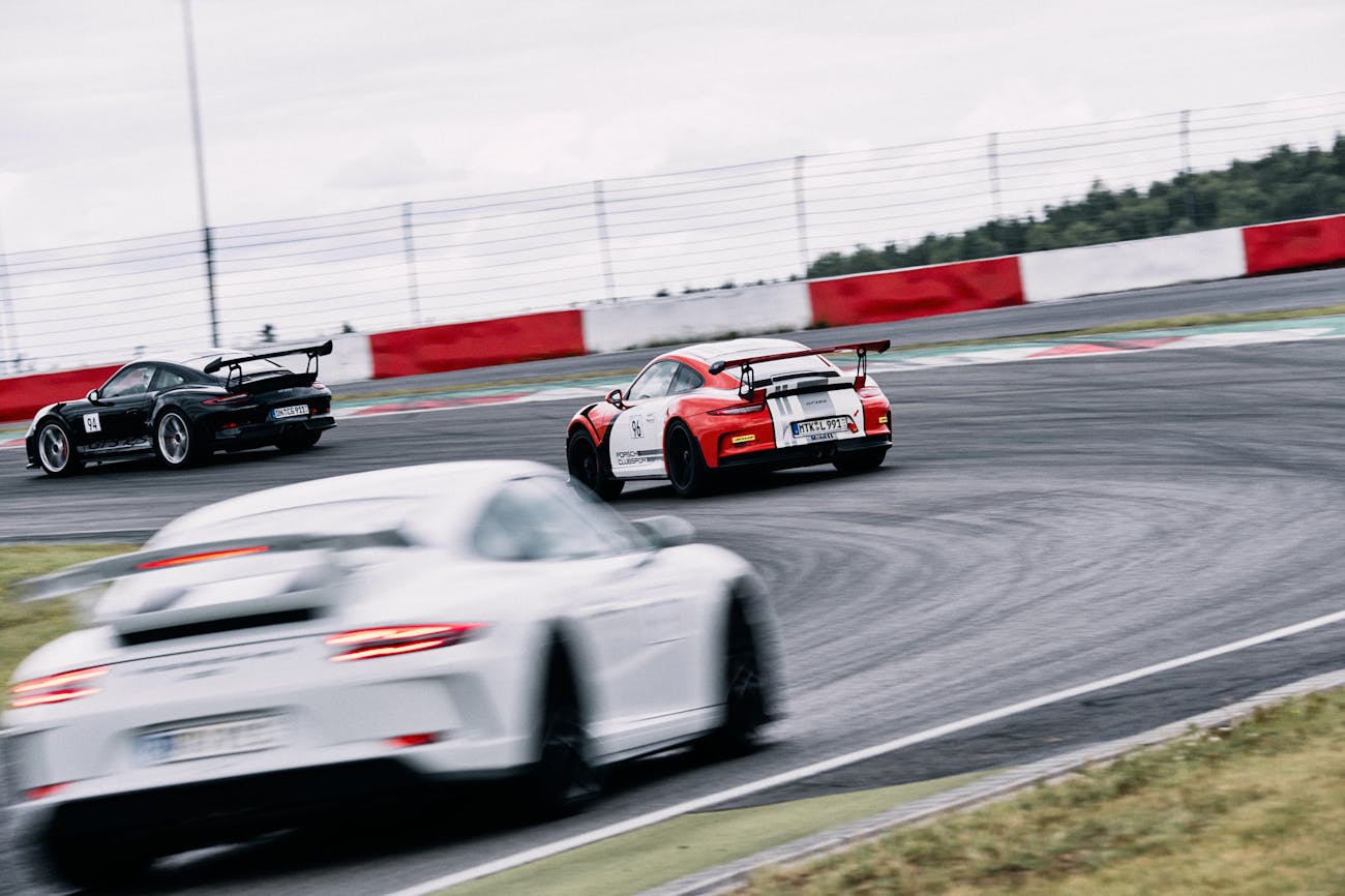 Three Porsche racecars follow each other on a racetrack
