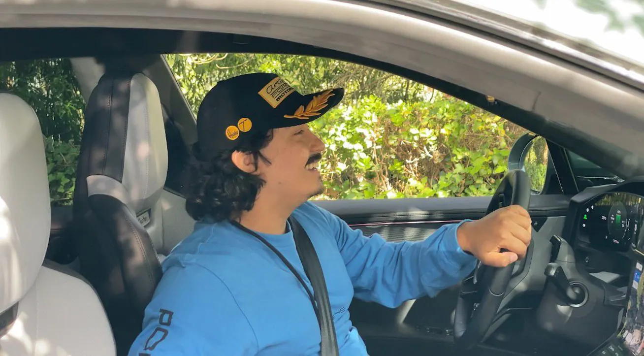 Smiling man in driving seat of Porsche Cayenne Electric 