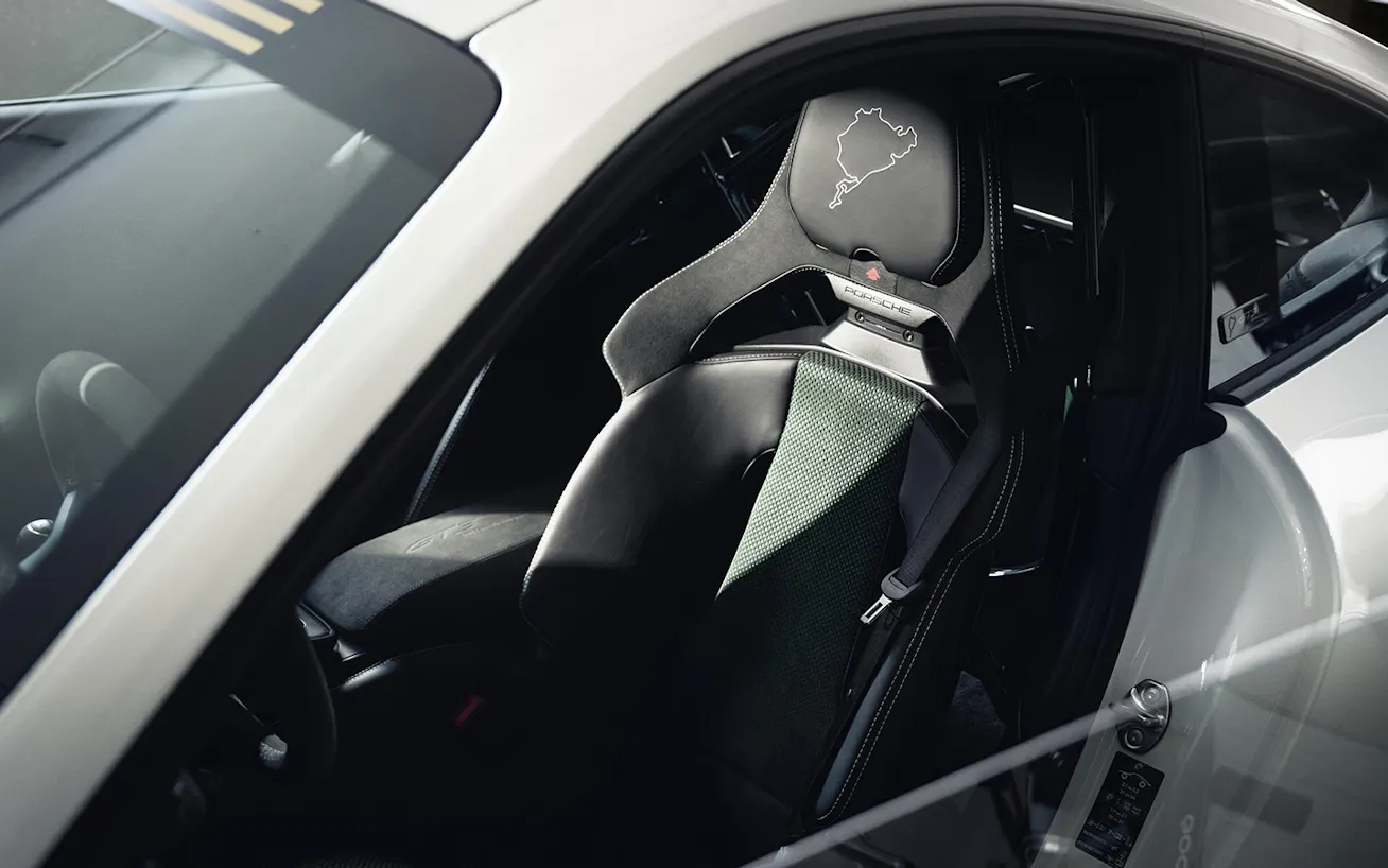 View of interior of Porsche 911 GT3 100 Jahre Nürburgring showing seats with embroidered map of Nürburgring race circuit on headrest