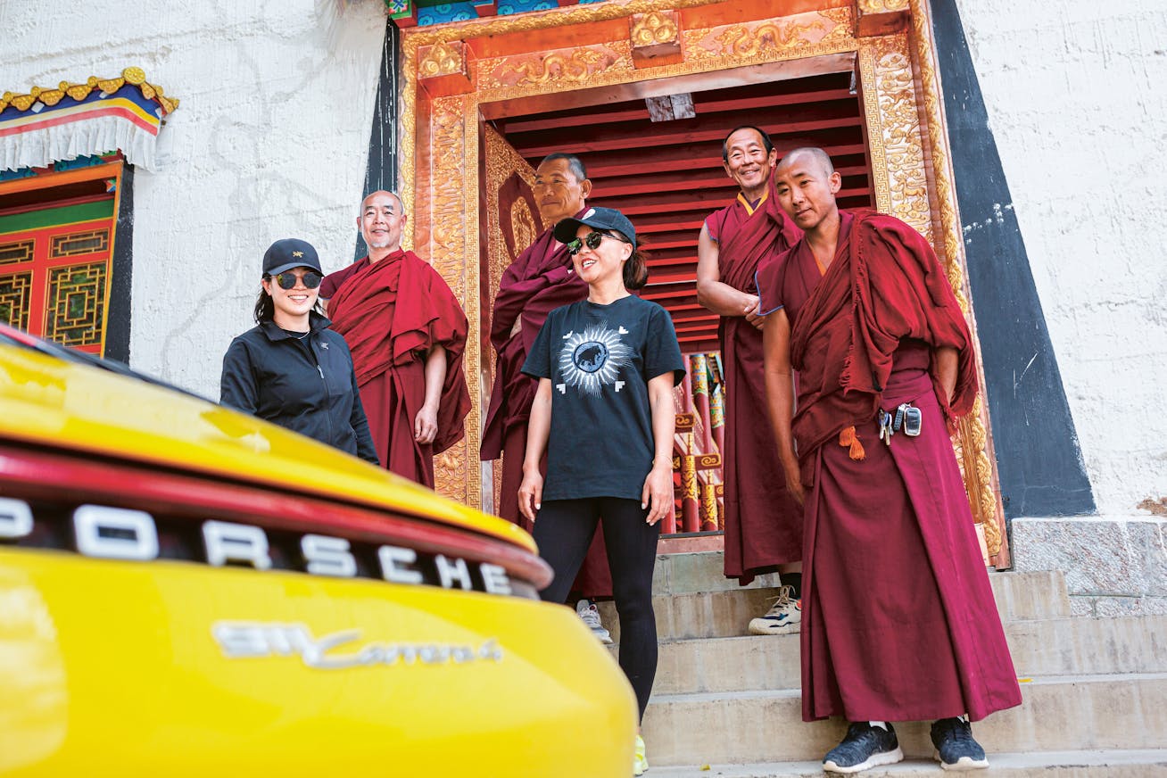 Yellow Porsche 911 Carrera is admired by Tibetan monks and two women
